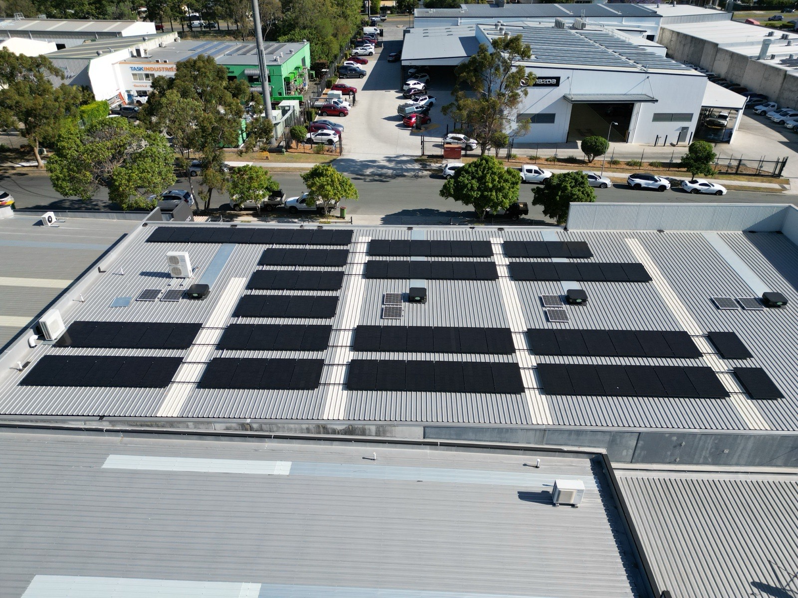 Overhead drone view of solar panels across a commercial warehouse roof